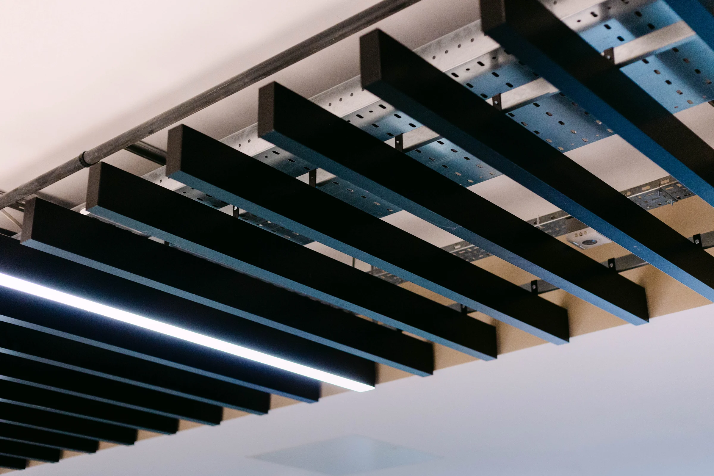 Architectural ceiling detail showing dark timber baffles with integrated linear lighting